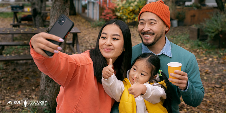 Asian family smiling and taking a selfie while on holiday